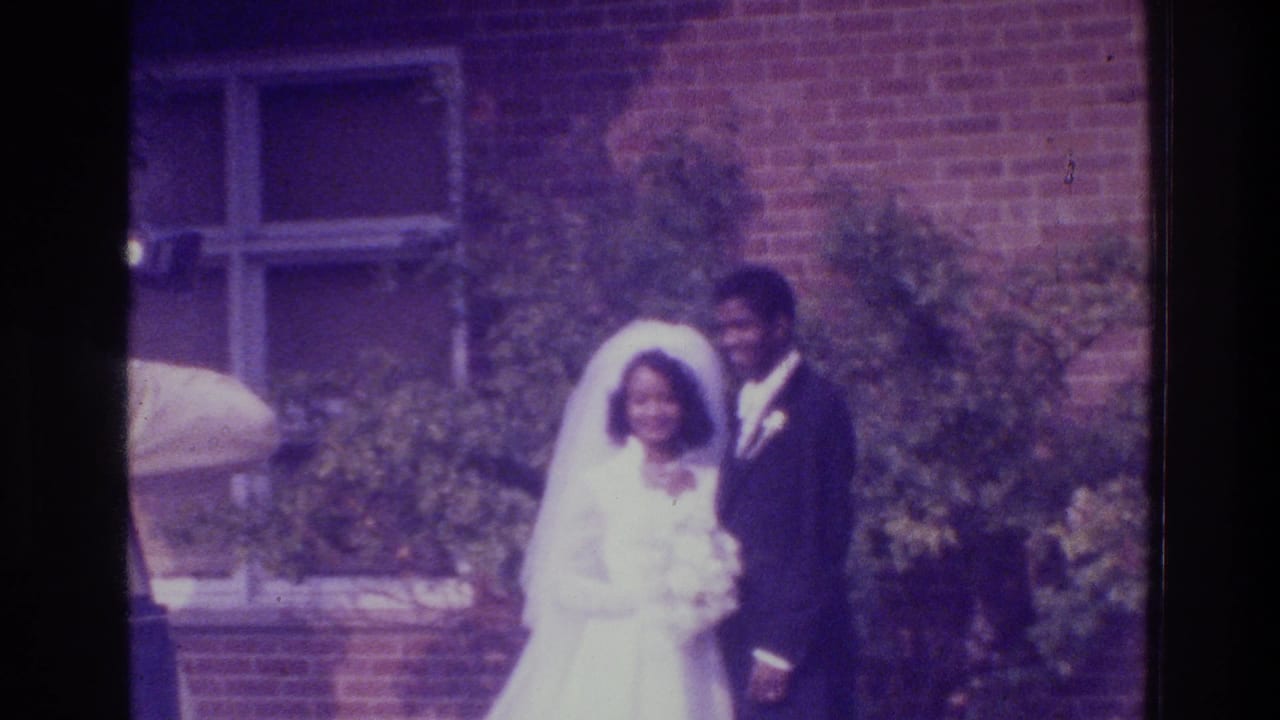 In 1975 Bronx home-movie footage, a bride in a white veil and groom in a dark suit pose outside a brick building.