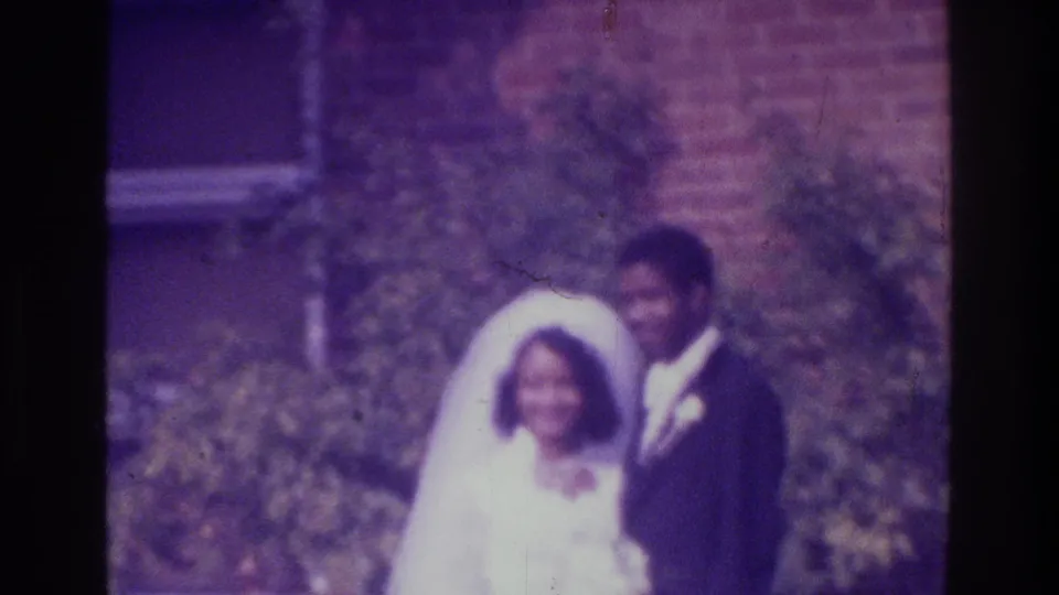 A closer soft-focus frame shows the 1975 Bronx bride and groom posing in front of greenery and a brick building.