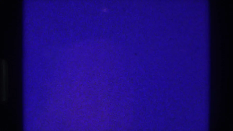 1975 Bronx 8mm frame with a dark vertical divider, saturated blue-purple lighting, warm reflected lights, and soft film grain.