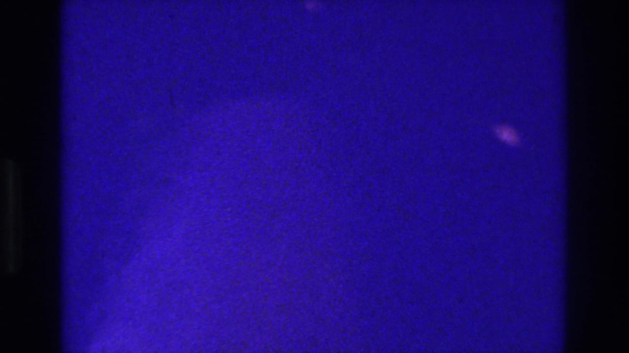 1975 Bronx 8mm frame dominated by deep blue exposure, black gate edges, and only faint indistinct shapes in the grain.
