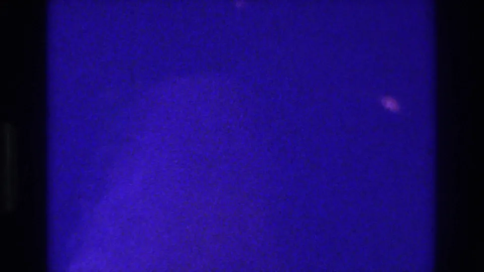 1975 Bronx 8mm frame dominated by deep blue exposure, black gate edges, and only faint indistinct shapes in the grain.