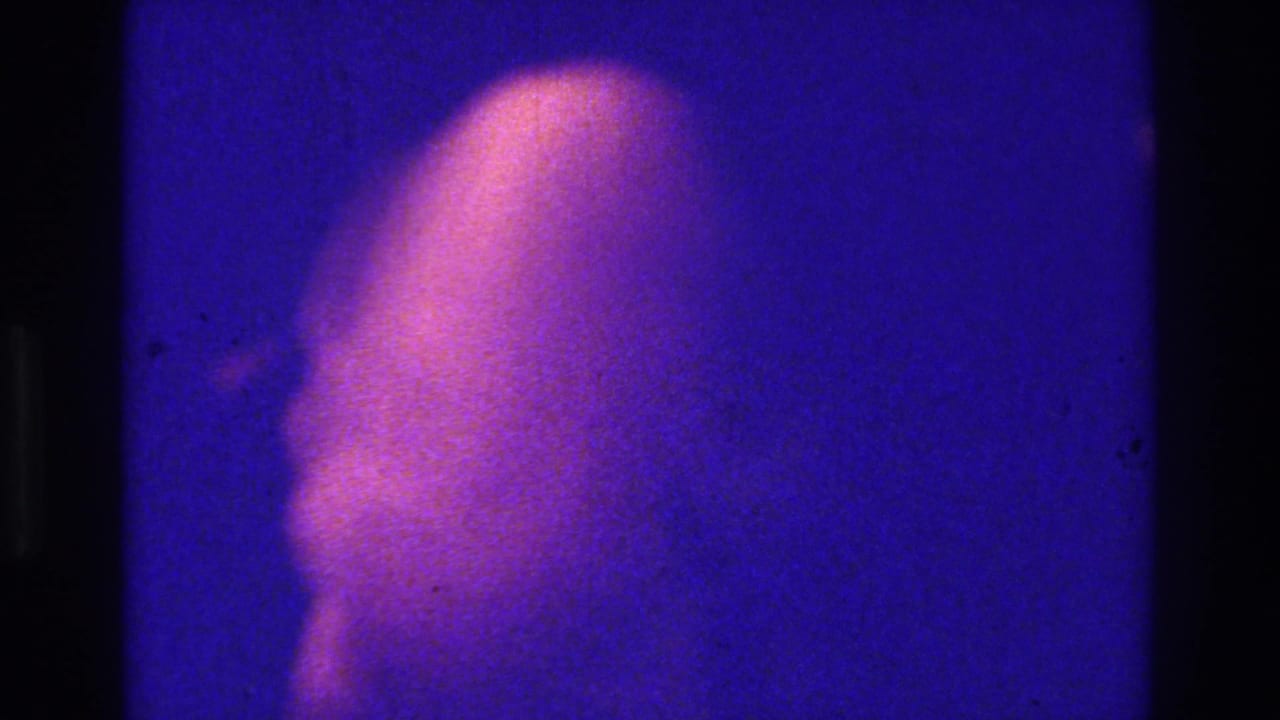 Pale purplish human-like shape against a dark blue grainy background.