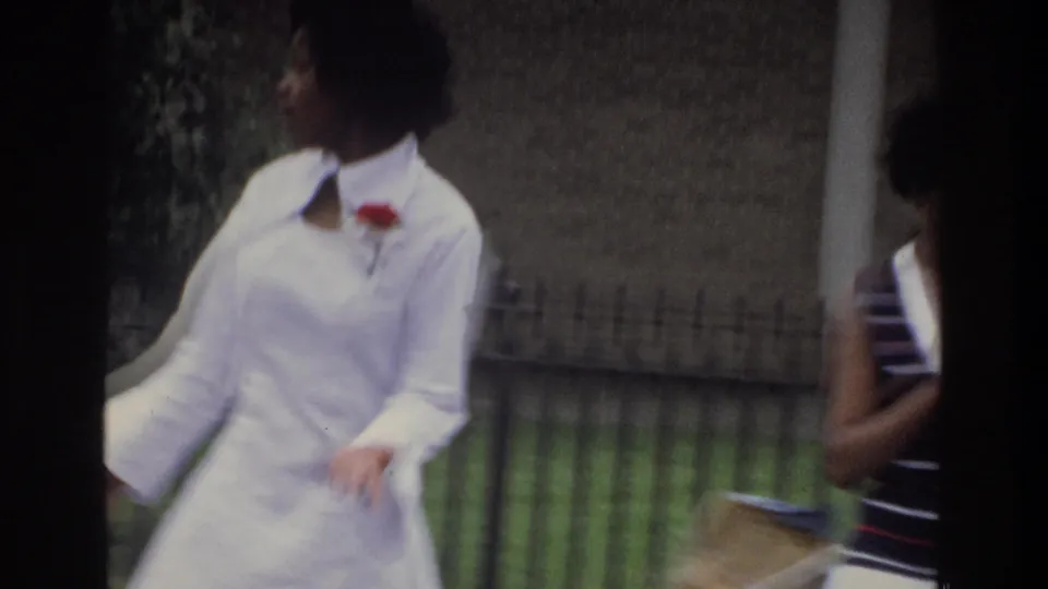 Handheld close shot of two women walking, identified as the Bronx, New York, circa 1975; wide white collar and red corsage visible through natural motion blur of 8mm filming.