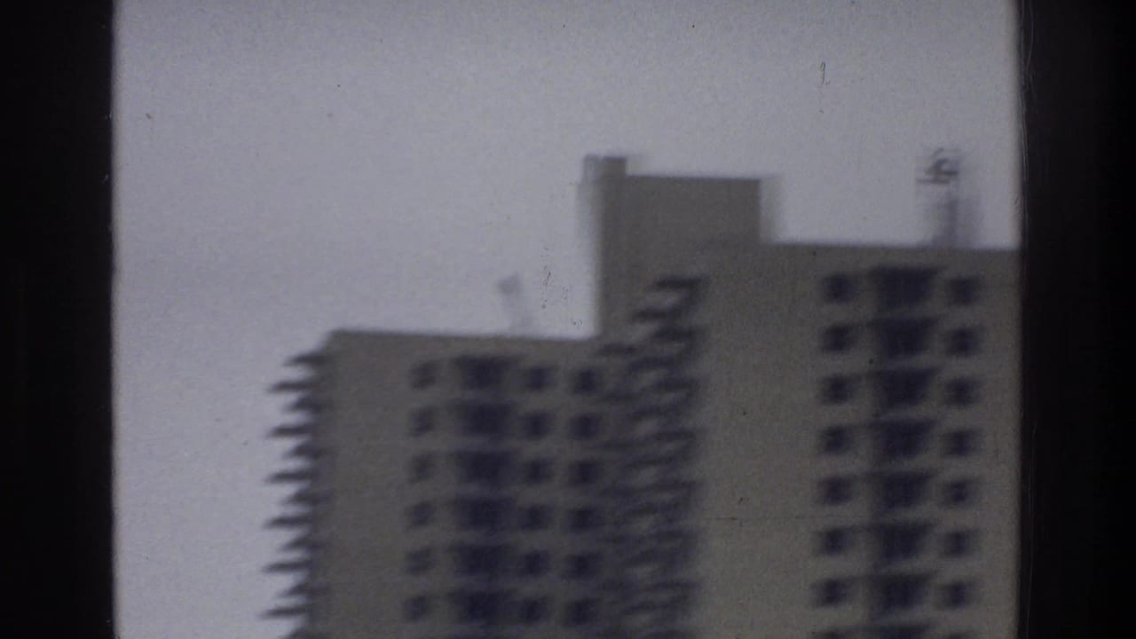 Soft 8mm view of Bronx high-rise apartment towers, with balconies and window grids blurred by vehicle motion.