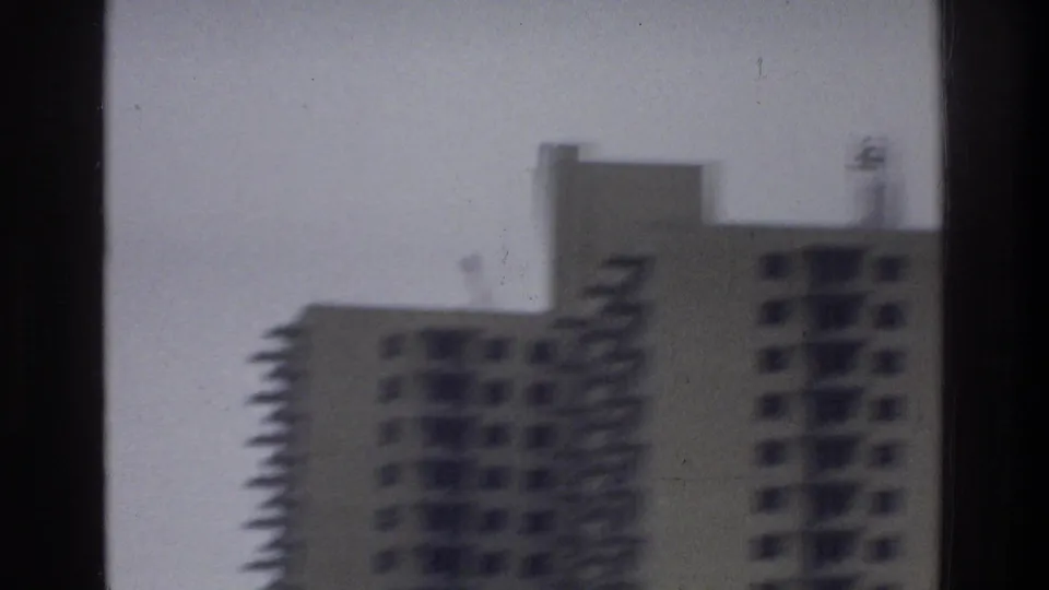 Soft 8mm view of Bronx high-rise apartment towers, with balconies and window grids blurred by vehicle motion.