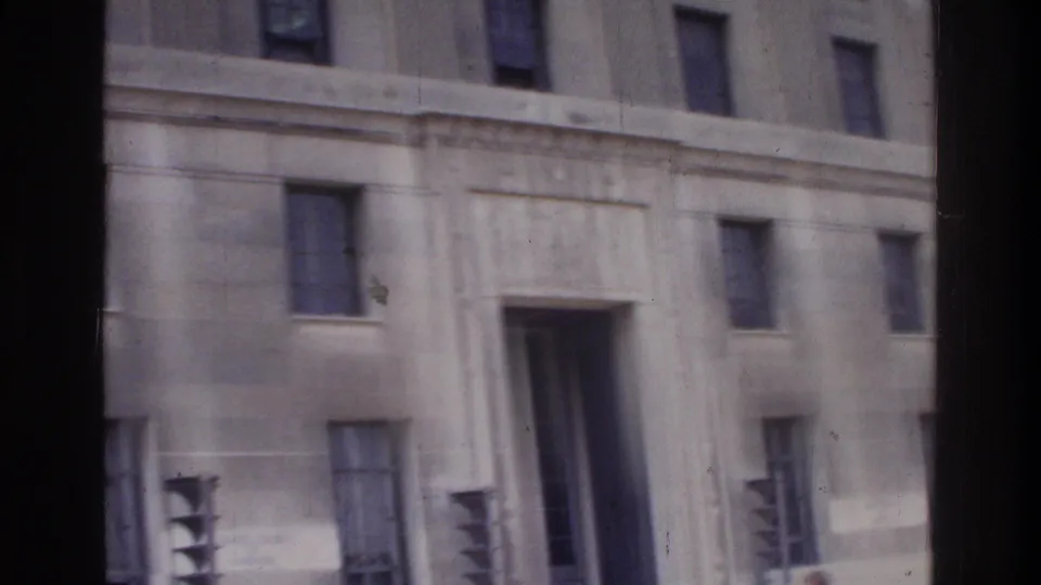 Panning close-up of a neoclassical federal-style stone building facade with pilasters and rectangular windows, Washington DC, circa 1975, 8mm home movie.