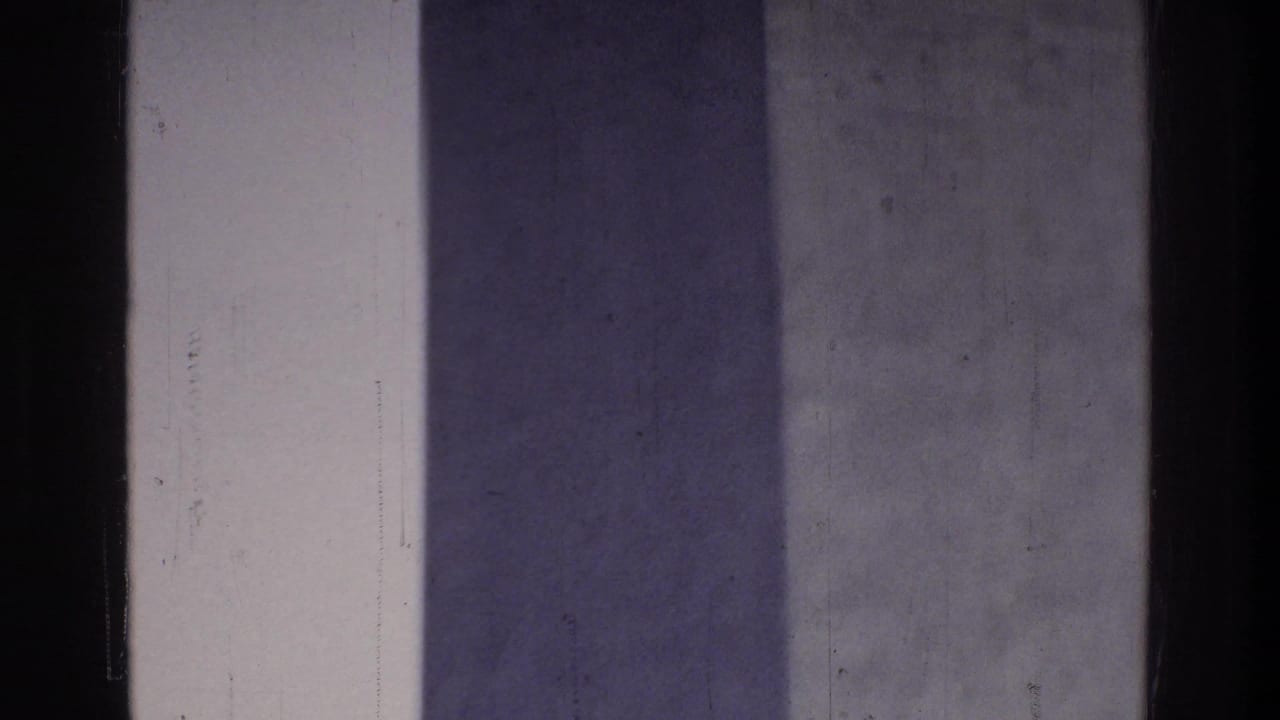 Extreme close-up of Washington Monument stone shaft filling the frame, pale sky at right edge, dark border at left, 8mm home movie