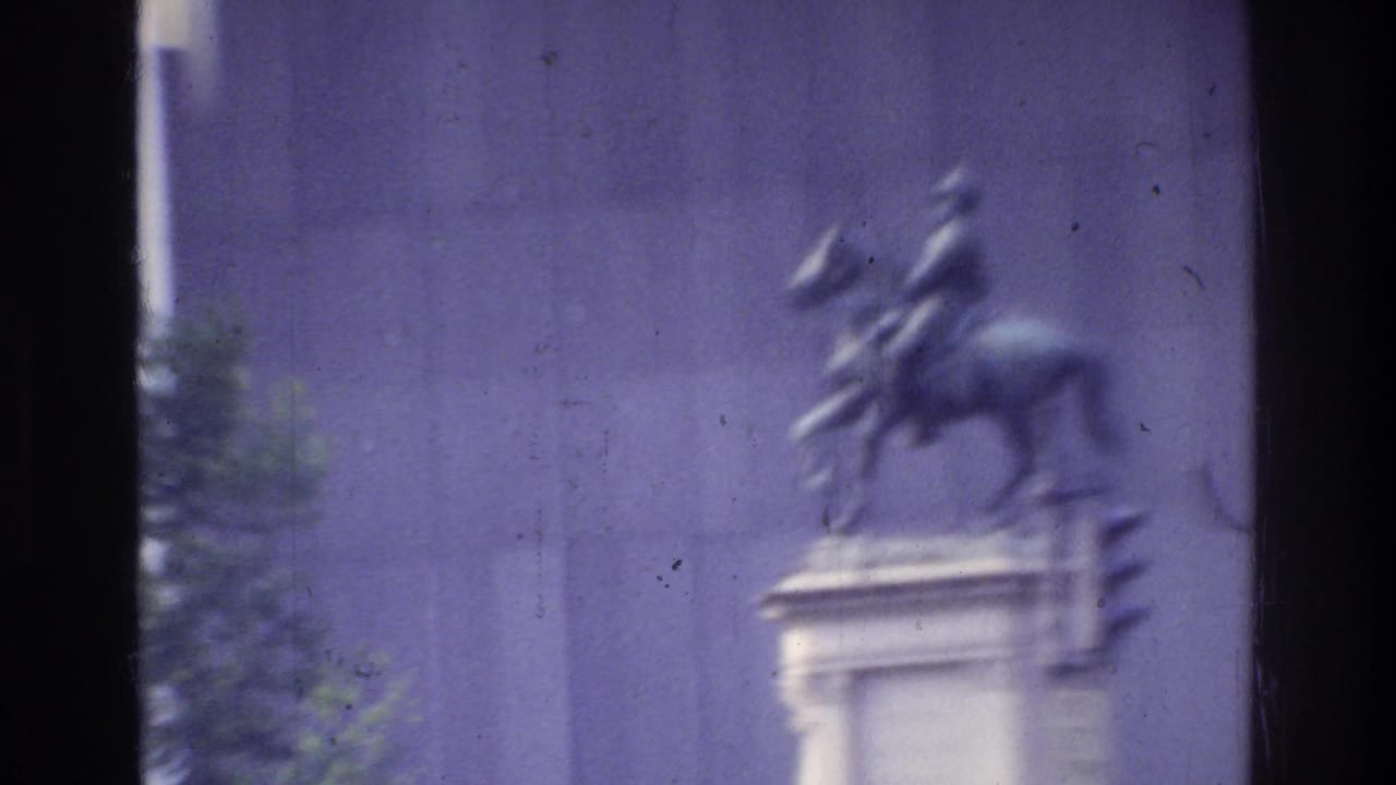 Bronze equestrian statue on a stone pedestal outside a large institutional building, likely a public monument in Washington DC, circa 1975; strong blue color shift from aged 8mm stock.