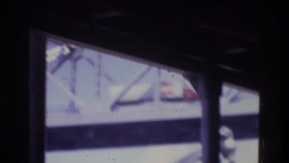 A dark foreground structure cuts across the view as a white truck and bridge structure remain visible in soft 8mm focus.