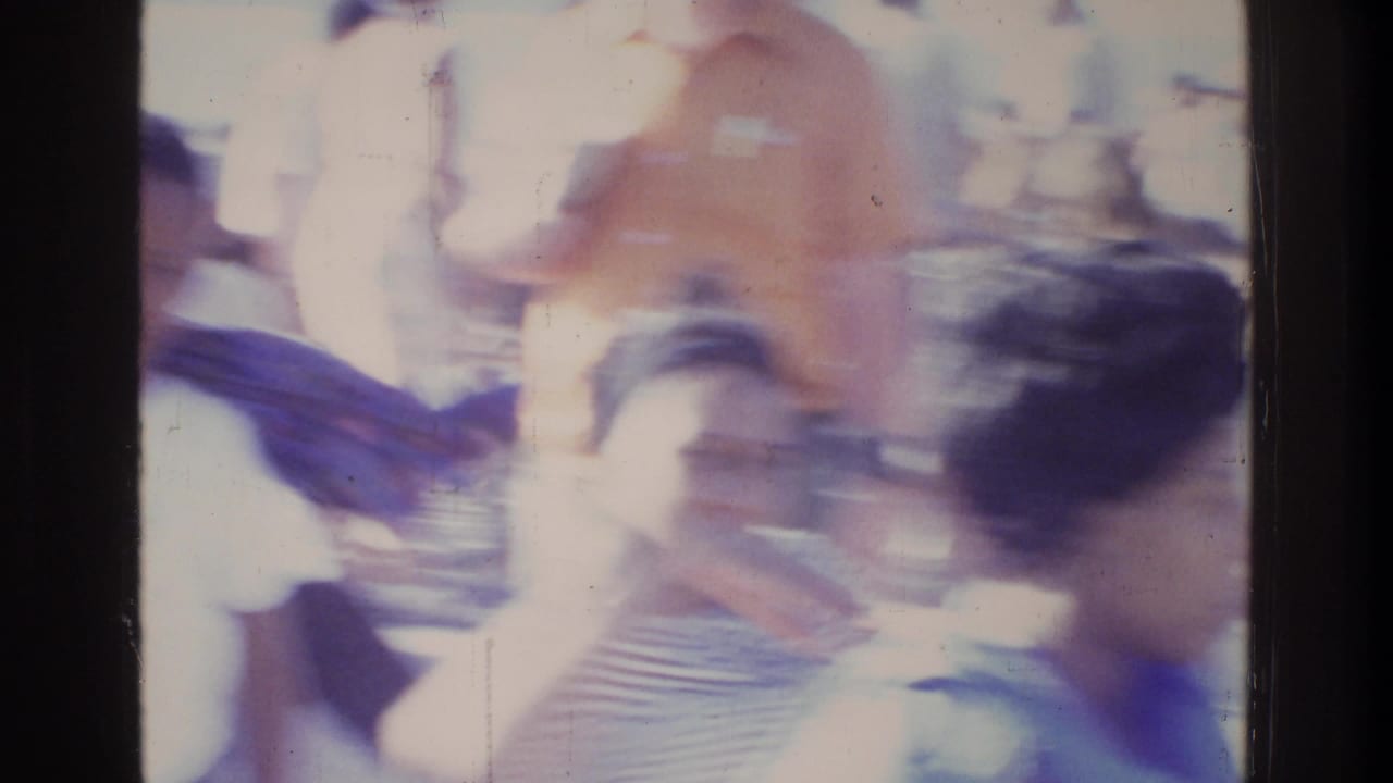 Camera-pan blur across a crowded outdoor gathering, Washington DC, 1975; orange and blue clothing visible among multiple figures.