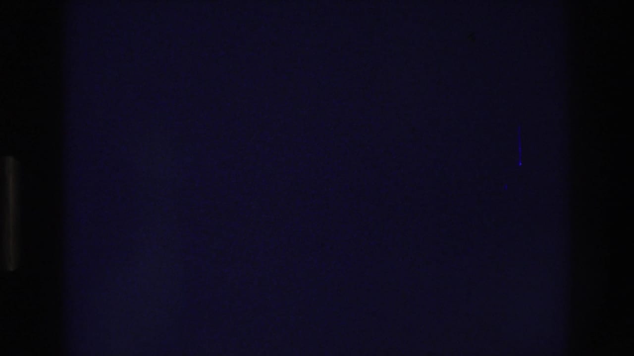 Unexposed or lens-capped dark frame from the opening seconds of a 1975 8mm home movie, showing film grain and a deep blue-black cast.