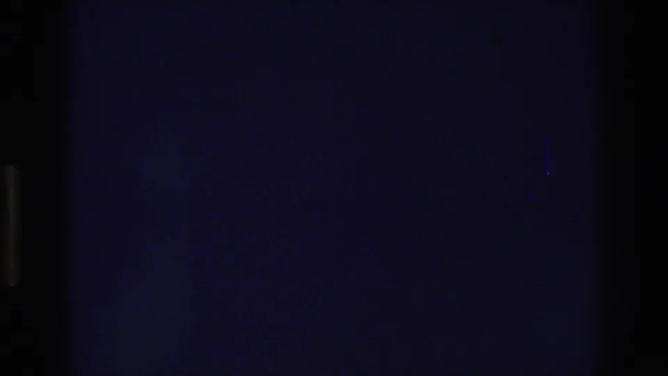 Unexposed or lens-capped dark frame from the opening seconds of a 1975 8mm home movie, showing film grain and a deep blue-black cast.