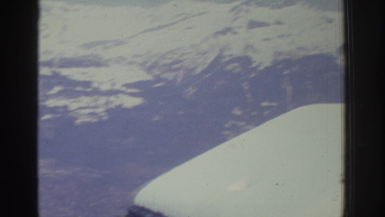 Alpine ridge and valley filmed through a vehicle window, likely Swiss Alps circa 1976, showing characteristic 8mm color fading and grain.