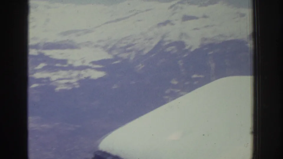 Alpine ridge and valley filmed through a vehicle window, likely Swiss Alps circa 1976, showing characteristic 8mm color fading and grain.