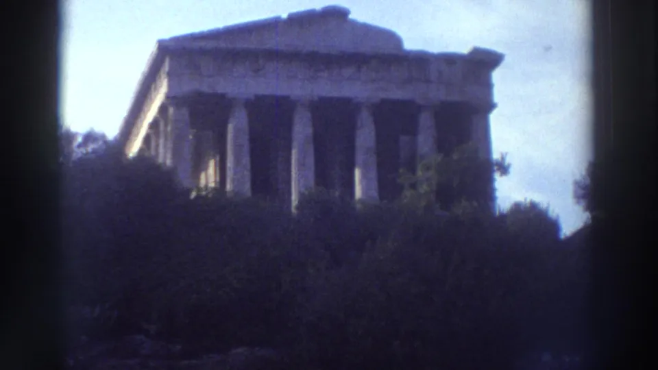 Full Doric colonnade of an ancient Greek temple in Greece, scrub vegetation at base, filmed on 8mm circa 1976