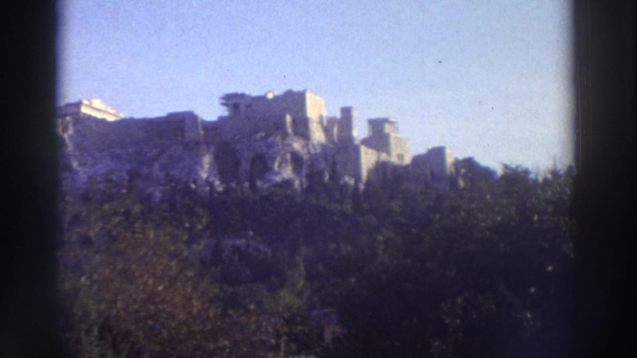 Wide 8mm shot of the Acropolis ruins rising above green hillside vegetation, Athens, Greece, circa 1976.