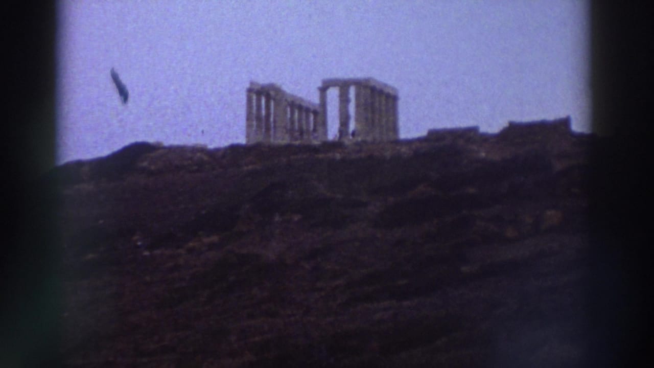 8mm home movie from Greece, c.1976: ancient columned temple ruins silhouetted on a rocky hilltop, lavender sky, a dark airborne object visible upper left.