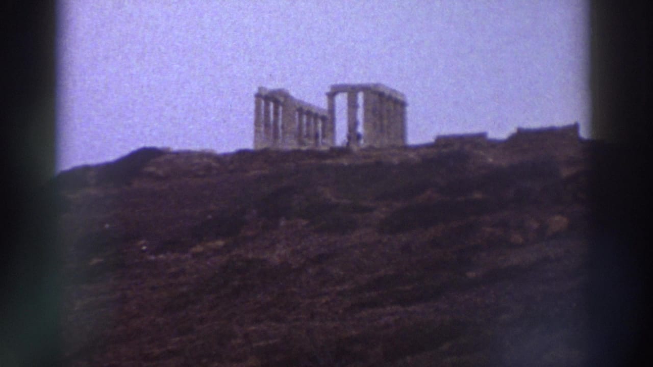 Ancient Greek columned ruins on a hilltop against a pale sky, slightly shifted framing from prior shot, film sprocket shadow at right.