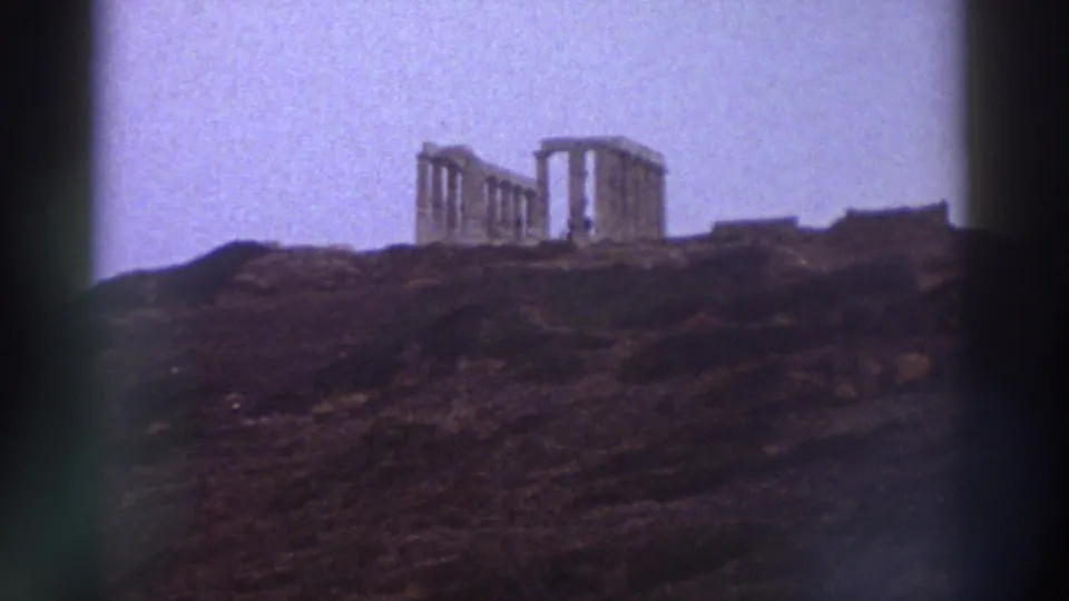 8mm home movie from Greece, c.1976: standing columns of an ancient temple on a rocky hilltop, lavender sky, film sprocket shadow at frame right.