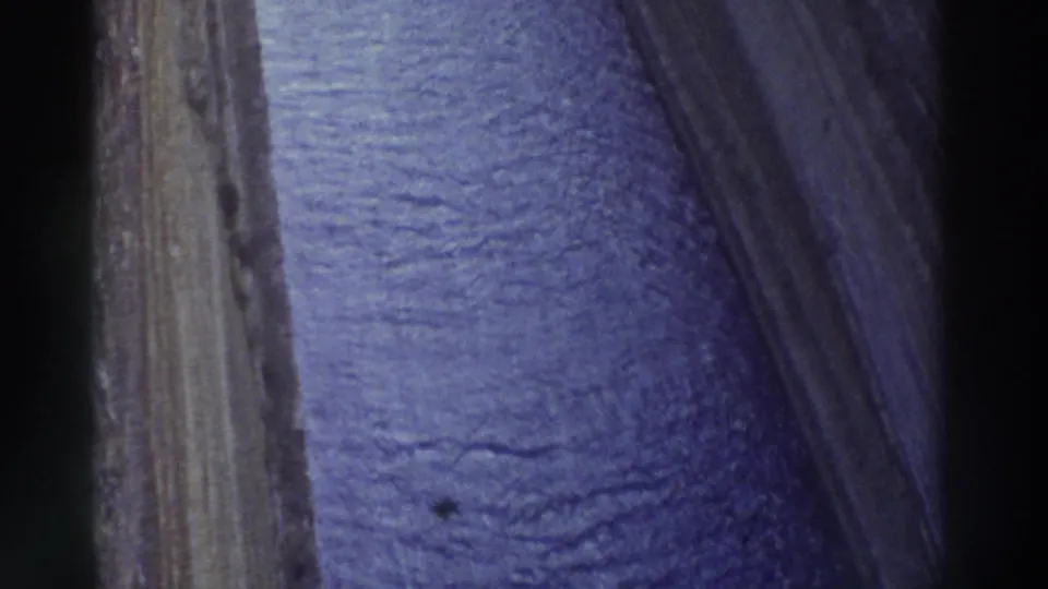 1970s 8mm footage of canal water viewed from nearly overhead, showing textured blue-purple surface and a vertical rock face at the edge, Greece 1976.