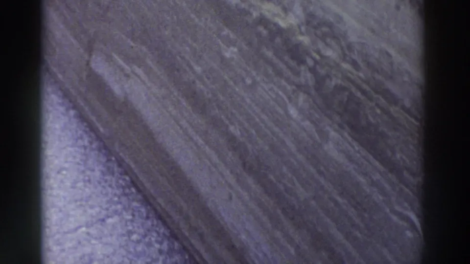 Macro shot of weathered stone with diagonal ridge line, lavender-purple color cast — 8mm home movie footage, Greece, 1976.