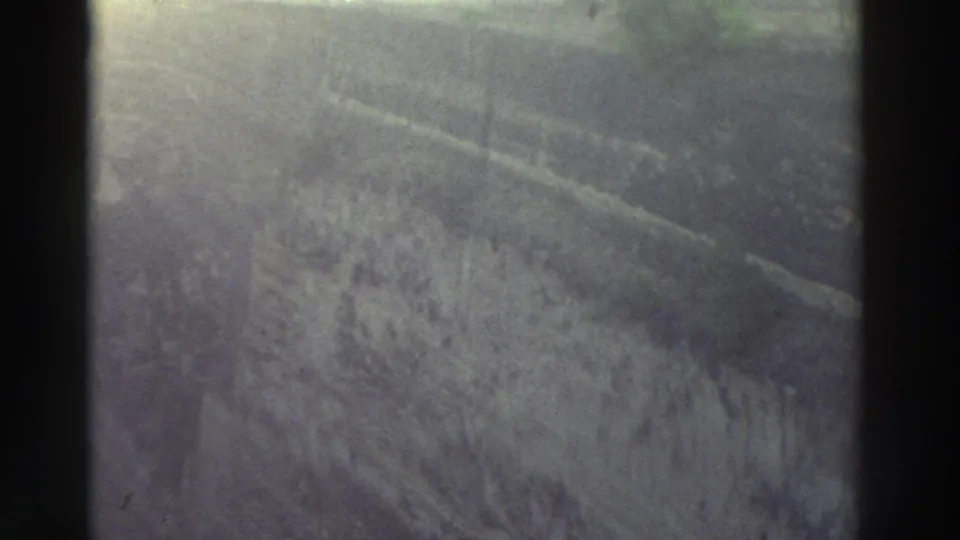 Macro shot of weathered rocky surface, gray-green cast with warm highlight band at top — 8mm home movie footage, Greece, 1976.
