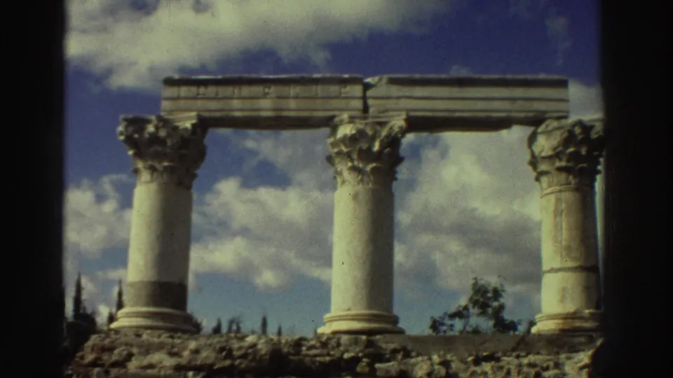 Three Corinthian-order columns with ornate carved capitals and partial stone entablature, filmed on Super 8 at ancient ruins in Greece circa 1976.