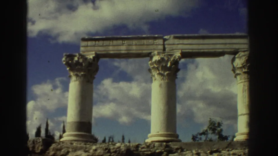 Row of Corinthian columns with acanthus-leaf capitals and stone entablature at ancient ruins in Greece circa 1976, filmed on Super 8 stock.