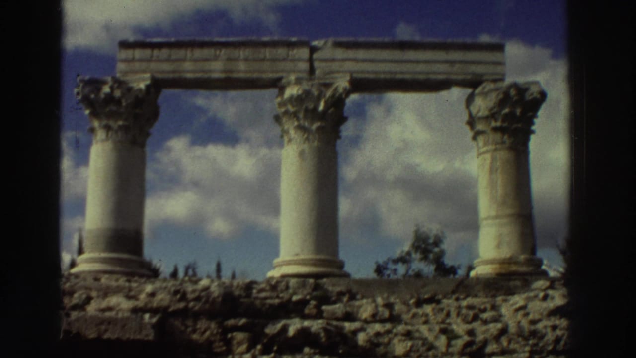 Four Corinthian columns at a Greek archaeological ruin site, circa 1976, shot on 8mm film; partial stone entablature and ruined foundation visible.