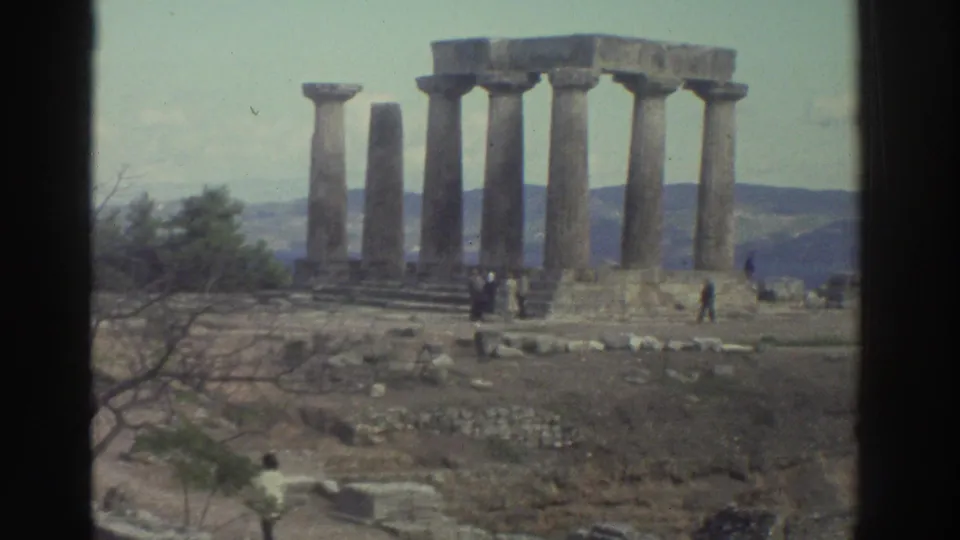 8mm amateur footage, likely Greece mid-1970s: standing Doric columns of an ancient temple on elevated terrain, distant visitors, mountainous horizon.