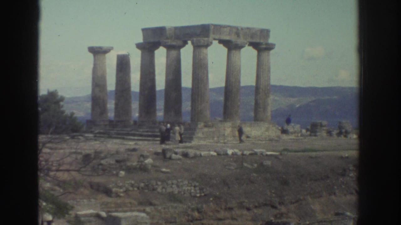 8mm wide shot of the same Doric column ruins from a similar angle, scattered visitors on rocky ground below.
