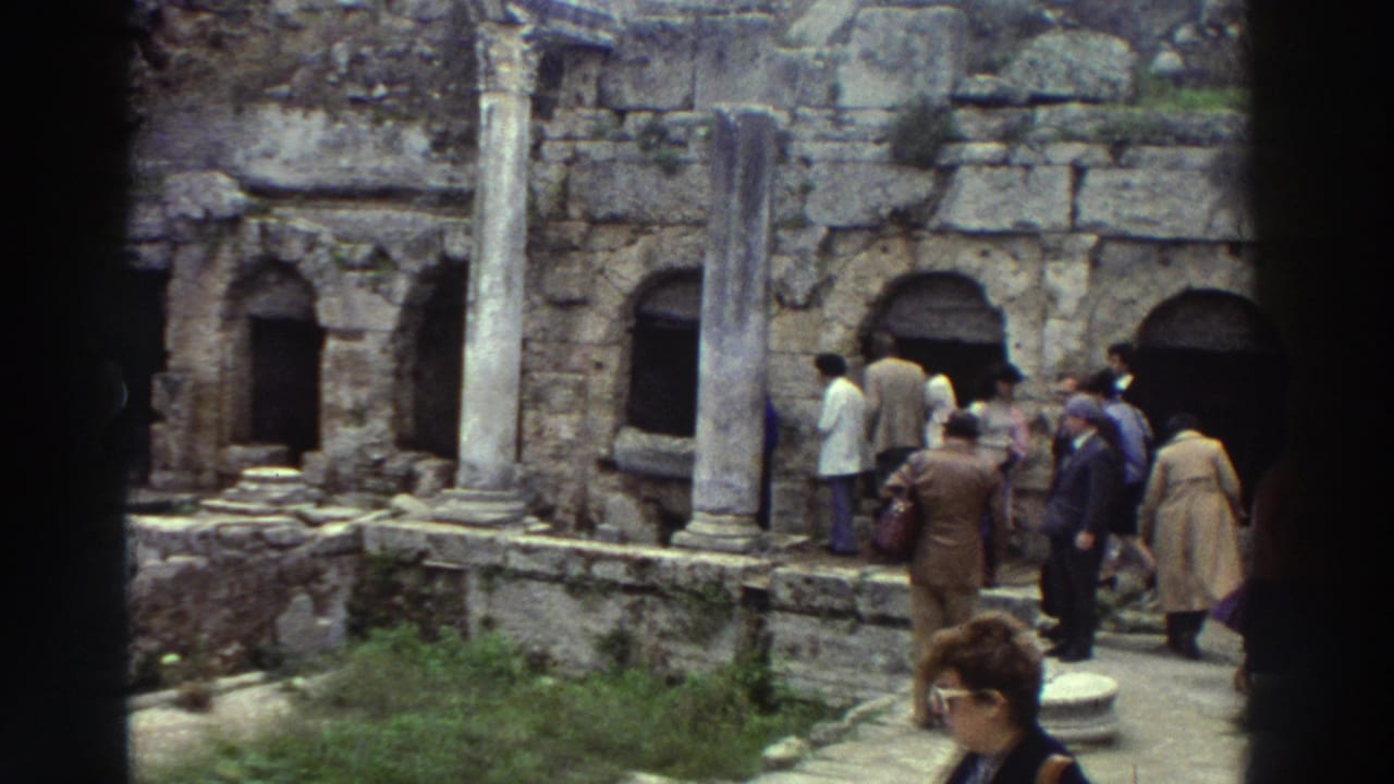 1970s tourists exploring a Greek classical ruin site, with arched stone niches, standing columns, and a woman in large-frame sunglasses close to the camera.
