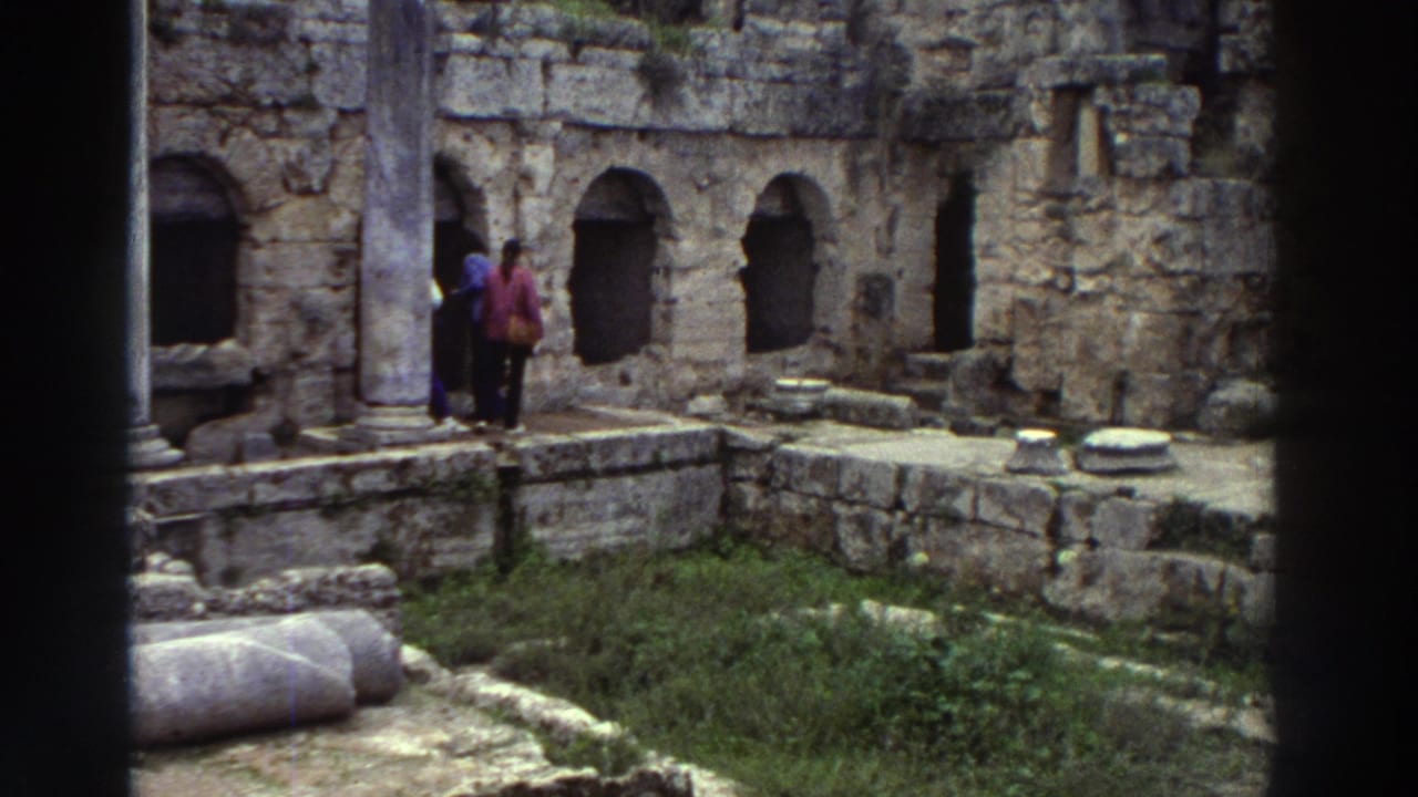 Two tourists in 1970s coats amid ancient stone ruins with arched niches and fallen column drums, Greece, 1976 8mm home movie.