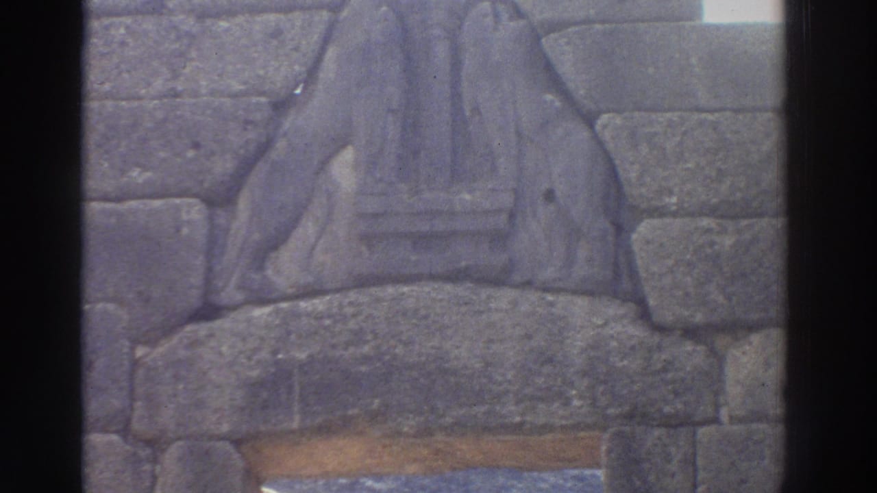 8mm close-up of the Lion Gate relief at Mycenae, Greece, c.1976, showing carved heraldic stone figures above the ancient threshold lintel.