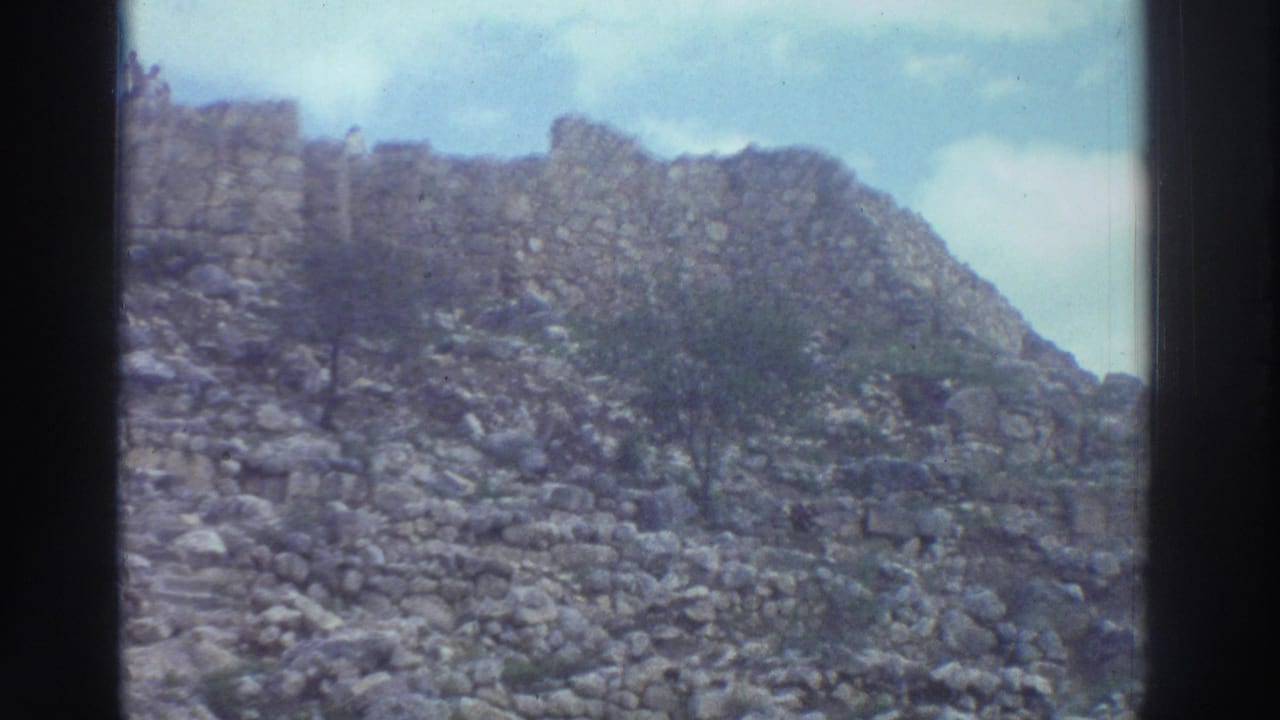 Rocky hillside covered in large stone blocks with an ancient wall remnant along the ridgeline