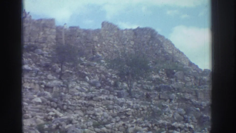 8mm footage of a rubble-covered hillside at a Greek ancient site with a remnant stone wall at the summit, circa 1976