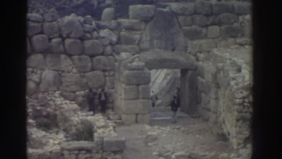 8mm shot of a monumental stone archway at an ancient Greek ruin site with a visitor passing through the gateway, Greece, circa 1976