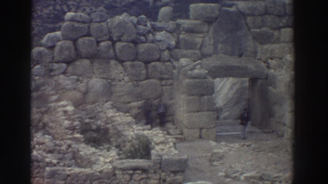Cyclopean-masonry gateway at an ancient Greek archaeological site, possibly in the Mycenae region, filmed on 8mm circa 1976; tourists visible at the base.
