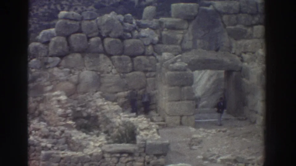 Cyclopean-masonry gateway at an ancient Greek archaeological site, possibly in the Mycenae region, filmed on 8mm circa 1976; tourists visible at the base.