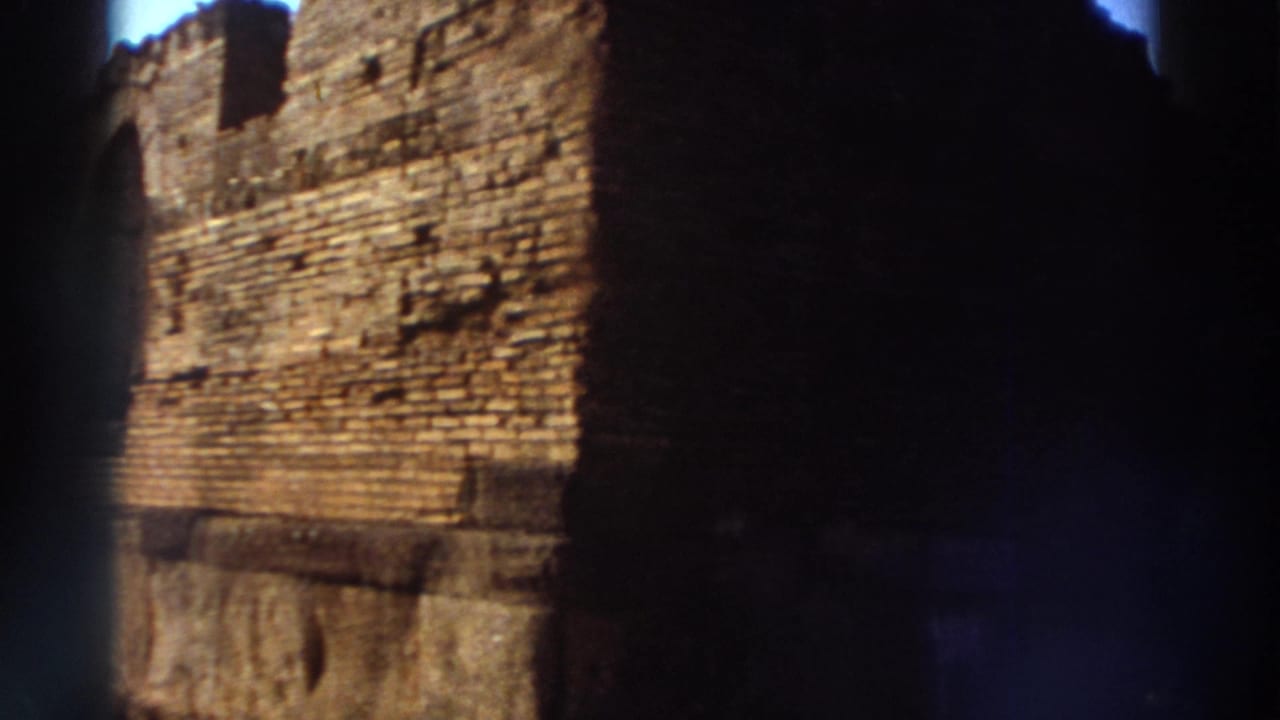 Large ancient stone wall filling the frame under direct sunlight with dark vignetting on both sides.