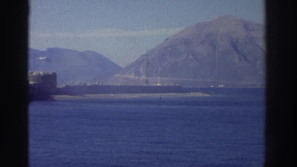 8mm footage from Greece, circa 1976, panning away from the fortress to show a prominent bare mountain dominating the coastal landscape.