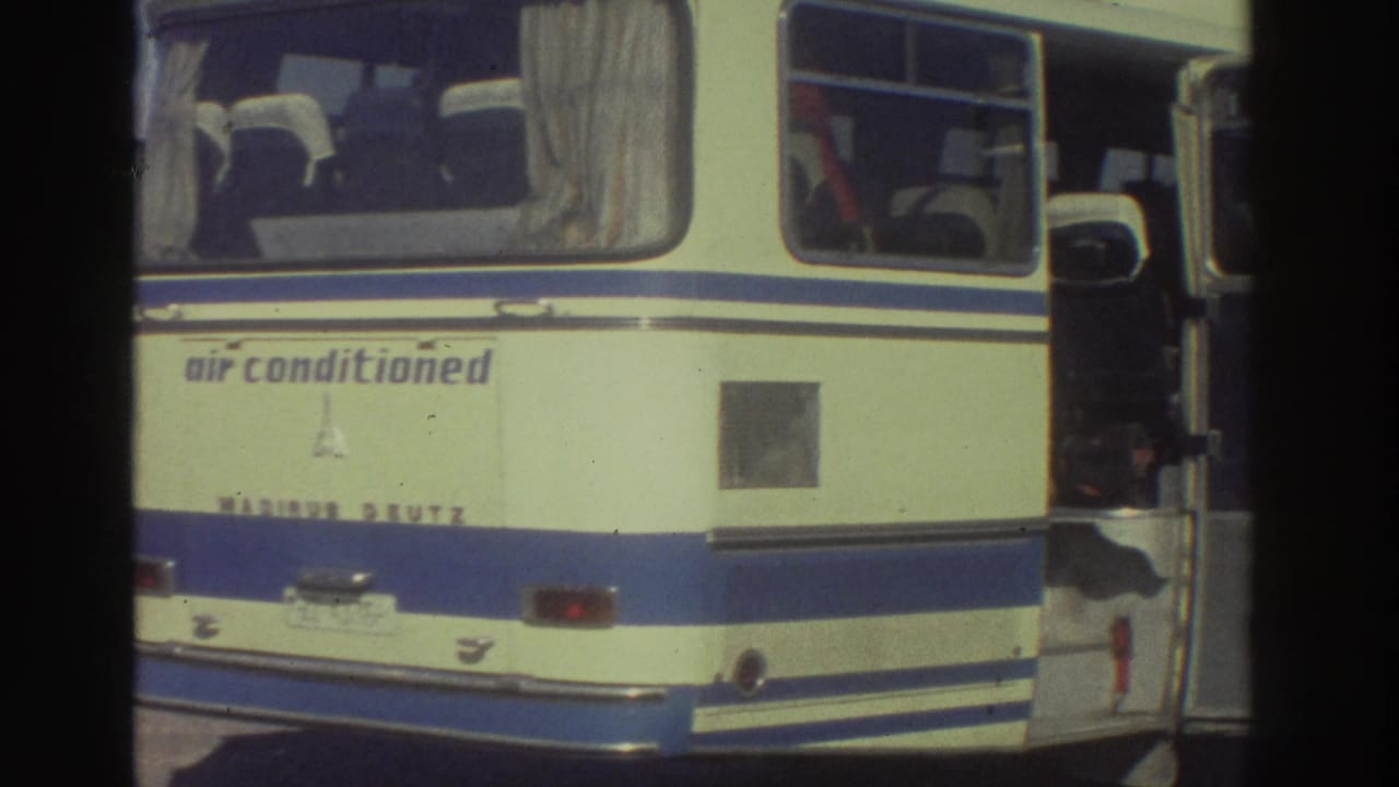 Rear of a cream-and-blue Magirus Deutz tourist coach with 'air conditioned' lettering on the body panel, 8mm home-movie footage from Greece circa 1976.