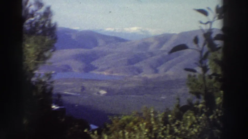 Super 8 home movie frame from Greece (c.1976) showing a broad mountain ridge, a hazy valley below, and what may be a snow-touched peak at upper right.