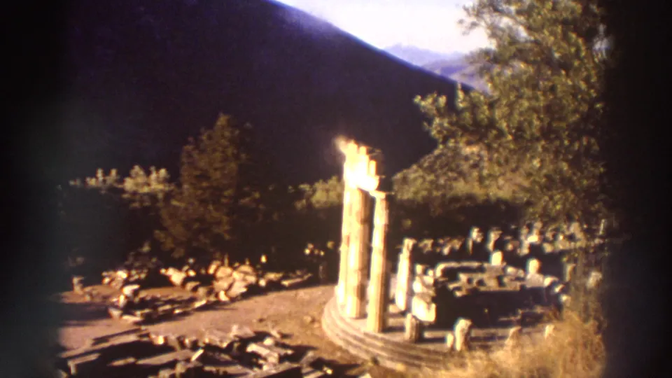 Ancient Greek ruins showing standing classical columns in a curved or circular arrangement, possibly a tholos, with rubble debris, filmed on 8mm in Greece circa 1976.