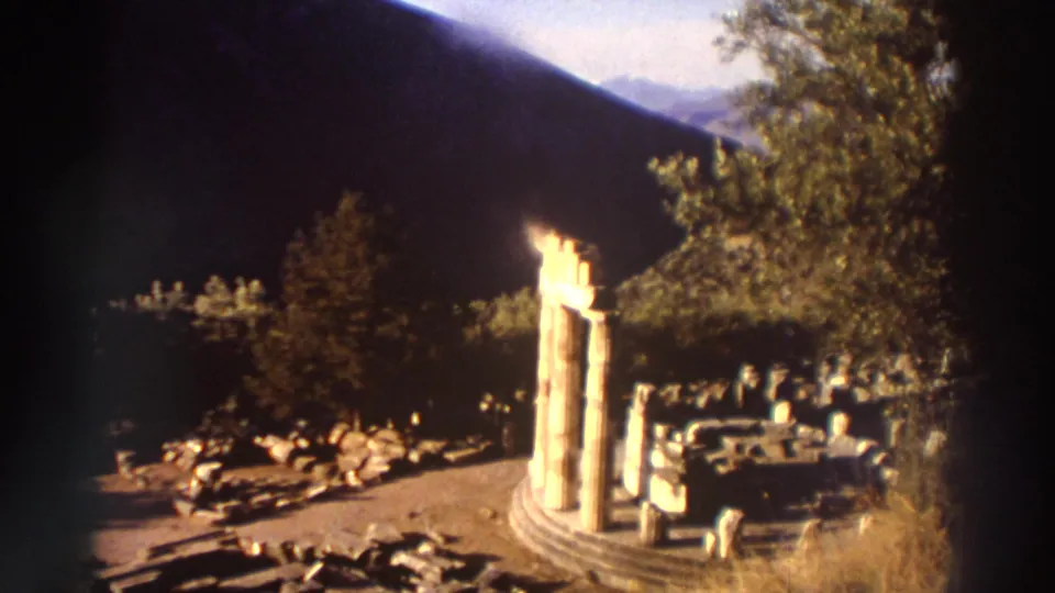 Three standing columns on a circular stepped base at a Greek archaeological site, 1976, 8mm home movie with warm tones and vignetting.
