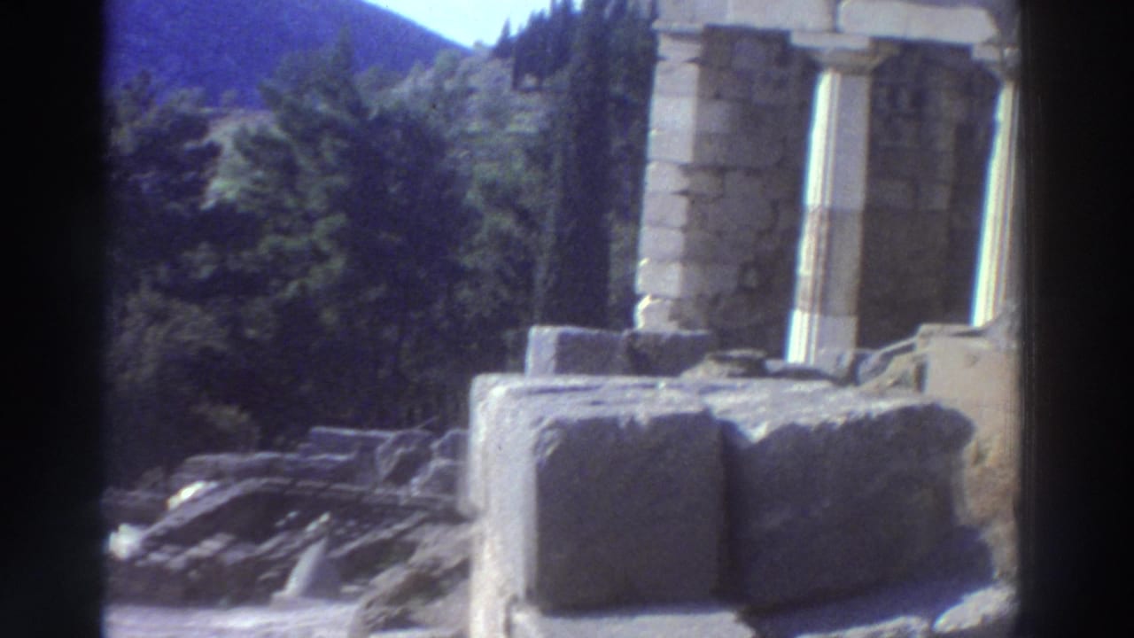 Close-up of ancient stone columns and fallen marble blocks at a Greek archaeological site.