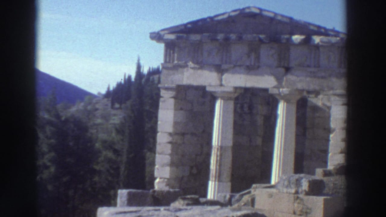 8mm home movie frame from Greece, c.1976, showing a small classical temple structure with Doric columns, triangular pediment, and stone steps.