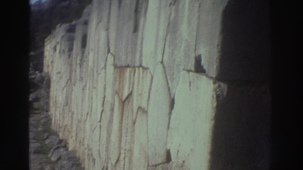 8mm home-movie frame showing towering weathered stone blocks at what appears to be ancient Greek ruins, circa 1976.