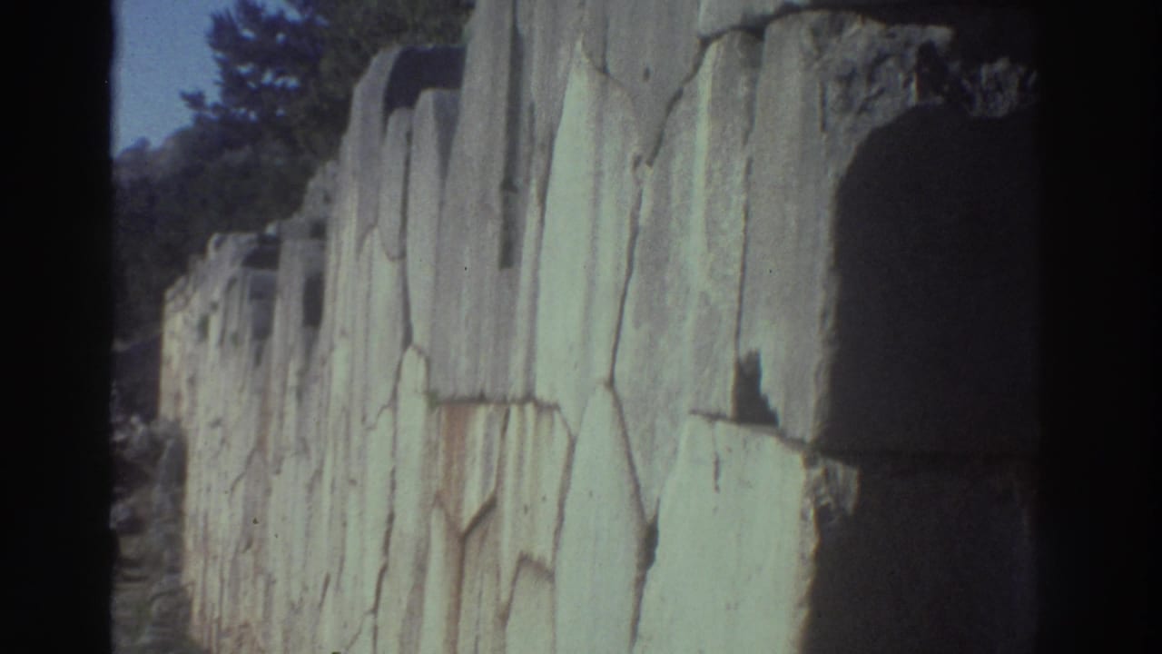 Large ancient stone wall with a monumental archway or gateway opening, trees and blue sky visible beyond.