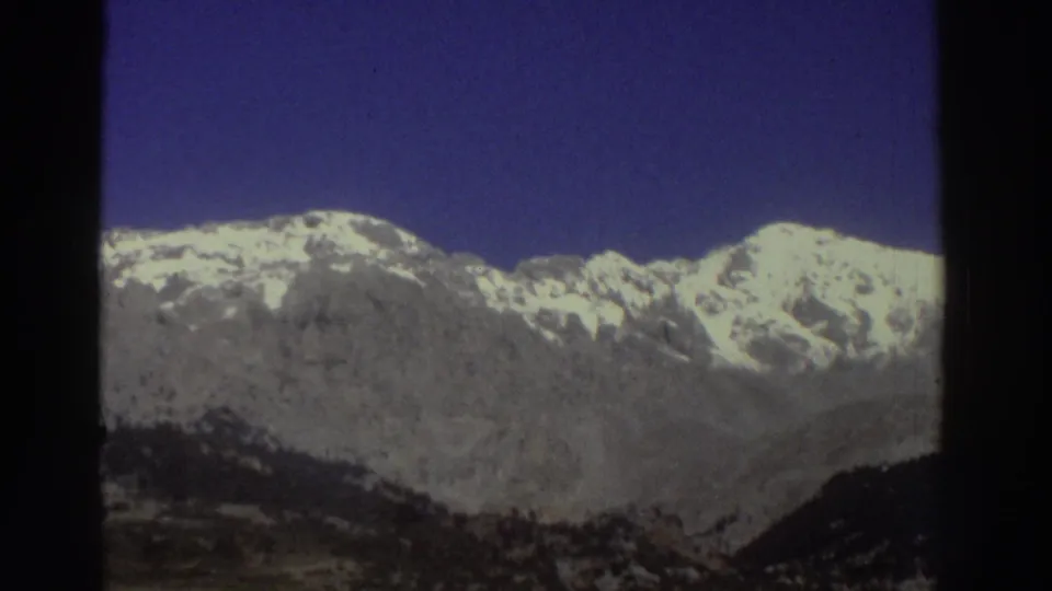 Snow-capped mountain peaks against a deep blue sky, circa 1976 Greece; saturated Super 8 color rendering highlights the bright snowfields and rocky outcrops.